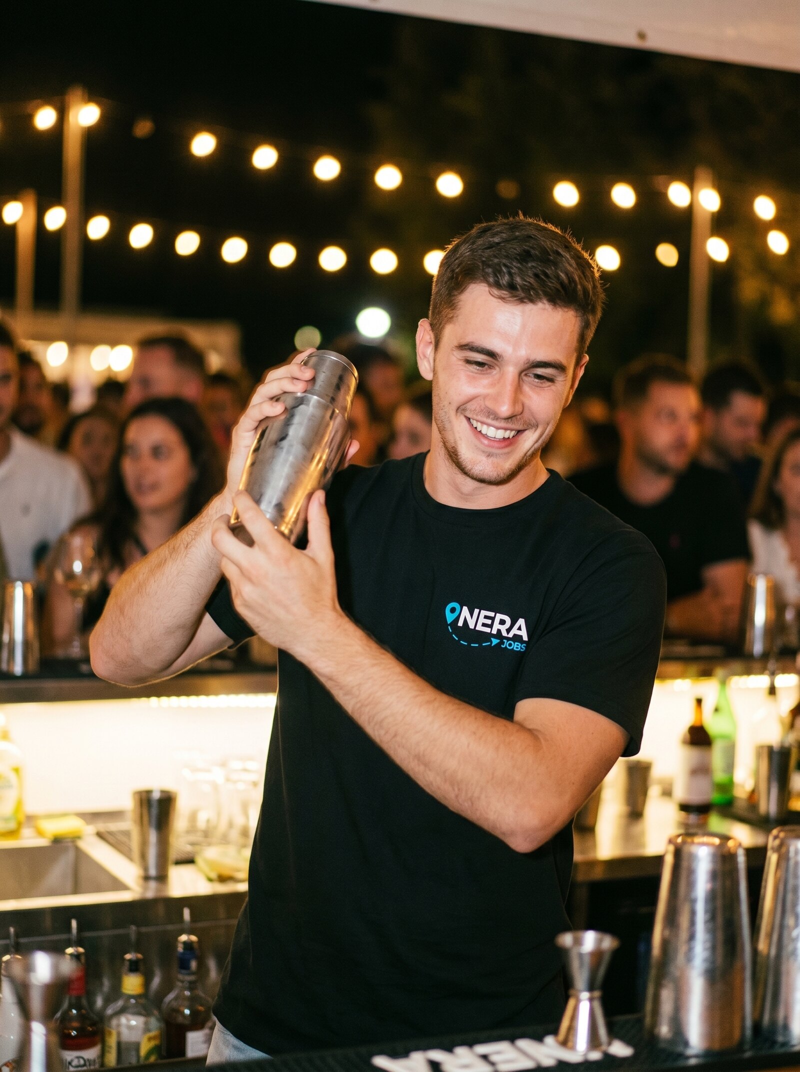 Bartender shaking a cocktail at an event bar in a NERA tee